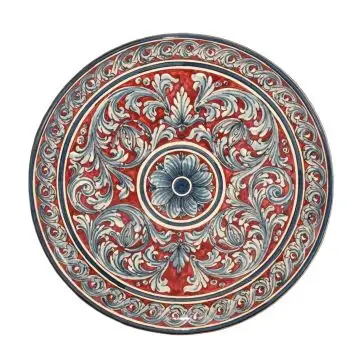 Sicilian wall plate hand-painted with an elaborate pattern on a dark pink background. The wall plate is handcrafted in Caltagirone, Italy.