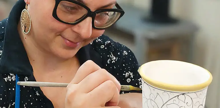 Marianna Mercante aka Andrilia painting an umbrella stand in her studio in Deruta