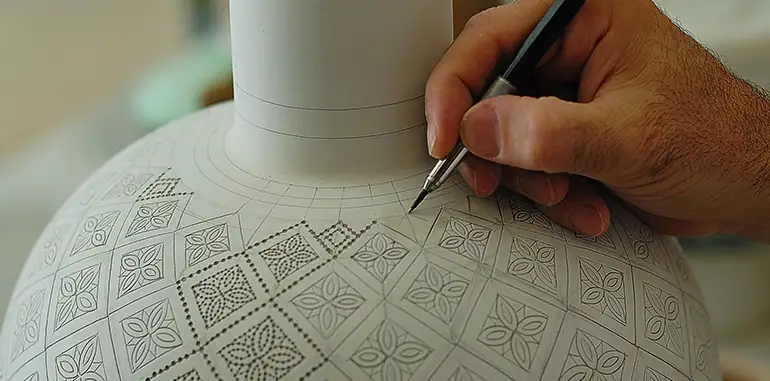 Francesco Fasano, a ceramic artist from Grottaglie, is scratching the design onto a table lamp.