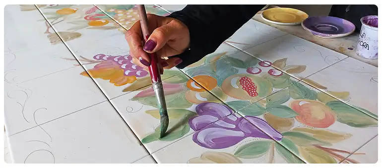 An artisan painting a backsplash panel